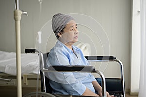 Depressed and hopeless Asian cancer patient woman wearing head scarf in hospital