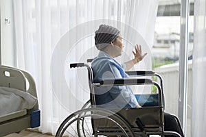 Depressed and hopeless Asian cancer patient woman wearing head scarf in hospital