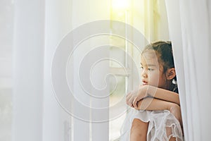 Depressed Little girl near window at home, closeup