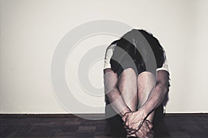 Depressed and lonely girl abused as young sitting alone in her room on the floor feeling miserable and anxiety cry over her life, photo