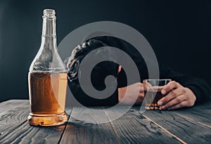 Depressed man drinking alcohol indoors