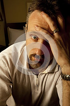 Depressed man in hotel room with head in his hand