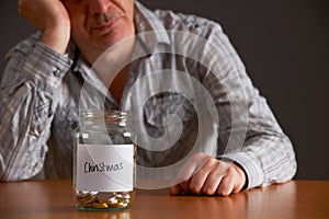 Depressed Man Looking At Empty Jar Labelled Christmas