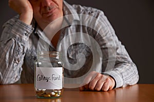 Depressed Man Looking At Empty Jar Labelled College Fund