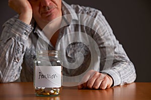 Depressed Man Looking At Empty Jar Labelled Pension