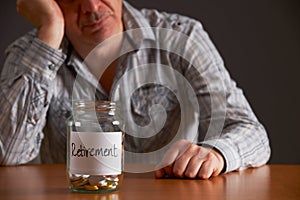 Depressed Man Looking At Empty Jar Labelled Retirement