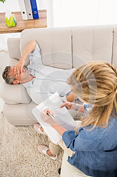 Depressed man lying on couch and talking to therapist