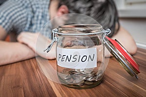 Depressed man lying on table. Pension savings in jar in front