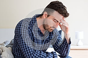 Depressed man portrait sitting on the bed