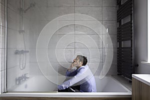 Depressed man sitting in bath