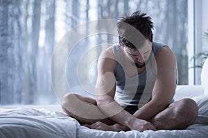 Depressed man sitting on bed