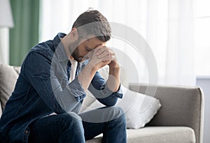 Depressed man sitting on couch in living room