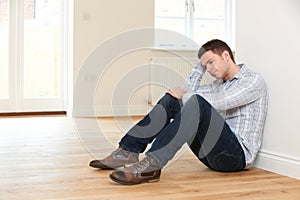 Depressed Man Sitting In Empty Room Of Repossessed House photo