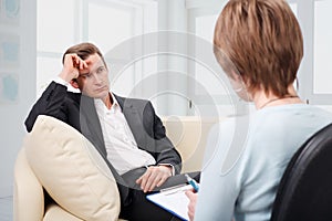 Depressed man talking with psychologist photo
