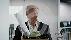 Depressed Mature Businessman Leaving Workplace Carrying Belongings In Box Indoor