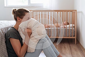 Depressed mother screaming with desperation in pillow to overcome negative emotions