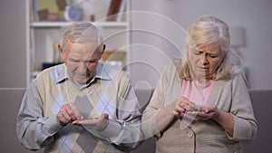 Depressed old couple counting coins in open palm, no money for living, poverty