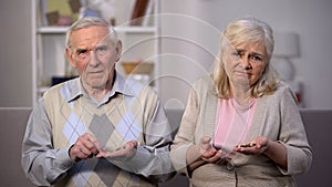 Depressed old people holding coins looking camera, pension age increase, poverty