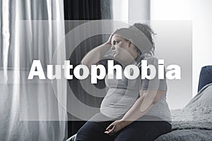 Depressed overweight woman sitting alone on bed. Autophobia