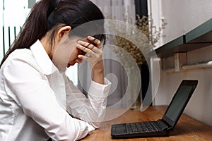 Depressed overworked young Asian business woman tired from work in office.