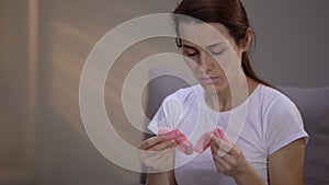 Depressed pregnant surrogate mother holding pink socks, psychological problems