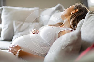 Depressed pregnant woman lying on the sofa with pain