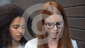 Depressed red-haired teenager eyeglasses suffering insulting classmate, conflict