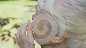 Depressed retired woman wiping tears outdoors, loss hopelessness, feeling lonely