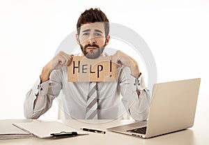 Depressed sad and frustrated young businessman holding a help sign in stress at workplace