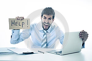 Depressed sad and frustrated young businessman holding a help sign in stress at workplace