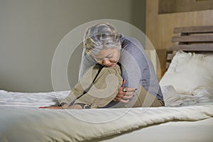 Depressed and sad grey hair mature woman crying lonely sitting on bed suffering crisis in pain and depression problem feeling lost