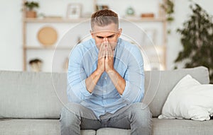 Depressed sad man sitting on couch, thinking about problems