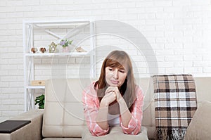 Depressed and sad middle aged woman sitting on bed, coach, sofa at home. Copy space and mock up.