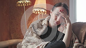 Depressed sad woman holding head in hands sitting on armchair at home. Lifestyle dramatic portrait of attractive and sad