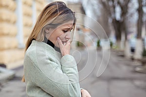 Depressed sad woman in profile almost crying on a city street