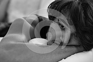 Depressed sad young man lying in bed. Black and white