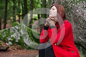 Depressed and sad young woman feeling depression sitting on forest, looking up with melancholic thinking