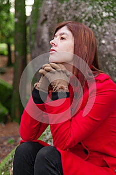 Depressed and sad young woman feeling depression sitting on forest, looking up with melancholic thinking