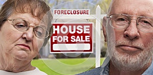Depressed Senior Couple in Front of Foreclosure Sign and House