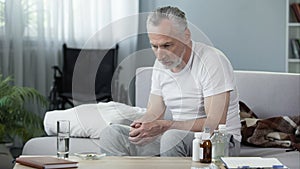 Depressed senior male sitting on sofa at nursing home, loneliness and melancholy