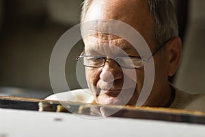 Depressed senior man in glasses sitting at the table and counting coins in a period of crisis. Pensioner poverty concept