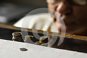 Depressed senior man in glasses sitting at the table and counting coins in a period of crisis. Pensioner poverty concept
