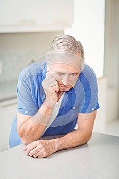 Depressed senior man leaning on table