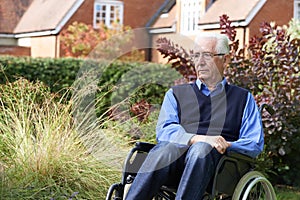 Depressed Senior Man Sitting Outdoors In Wheelchair