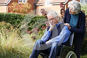 Depressed Senior Man In Wheelchair Being Pushed By Wif photo