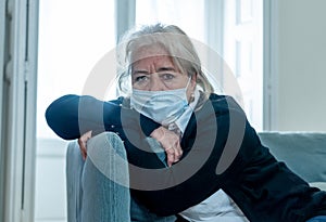 Depressed senior widow woman with protective mask alone at home feeling sad and missing family