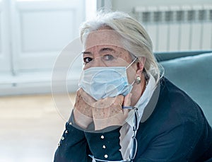 Depressed senior woman with facemask feeling lonely after loosing husband due to coronavirus