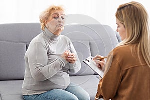 Depressed senior woman talking with female psychologist