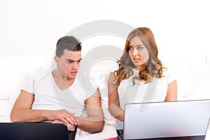 Depressed and shocked young man looking at woman's computer