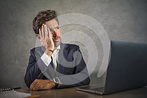 Depressed and stressed attractive hispanic businessman in suit and tie working  exhausted at office computer desk frustrated and